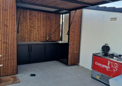Cocina exterior finalizada en metal y madera junto a piscina.